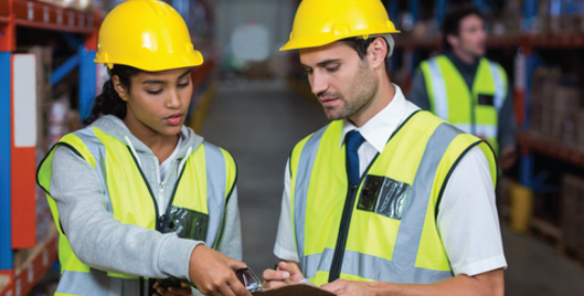 Two people in high vis jackets and hard hats conducting a risk assessment