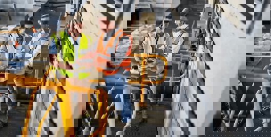 Two men stood in warehouse discussing information on a clipboard