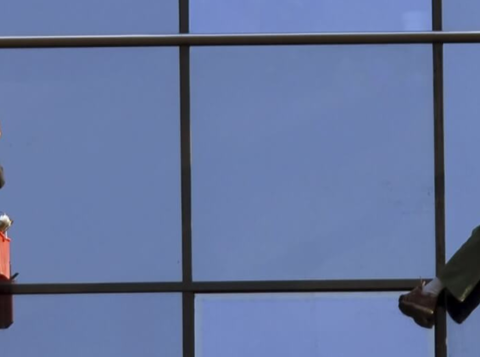 Two window cleaners working at height wearing PPE