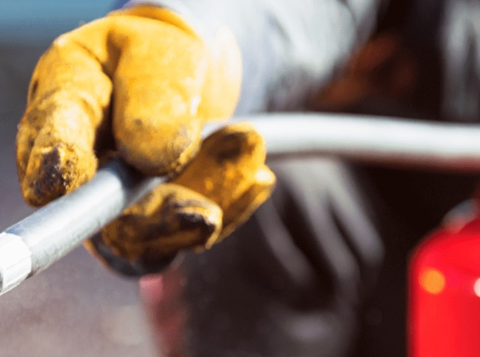 Person spraying a fire extinguisher wearing yellow protective gloves